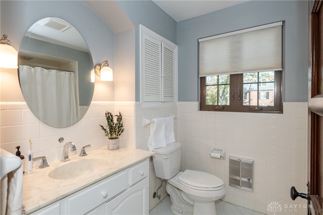 bathroom featuring vanity, heating unit, toilet, and tile walls