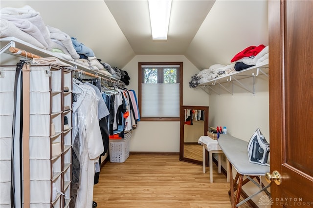 spacious closet featuring light hardwood / wood-style floors and lofted ceiling