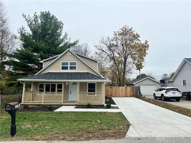 view of front of property featuring an outbuilding, covered porch, a front yard, and a garage