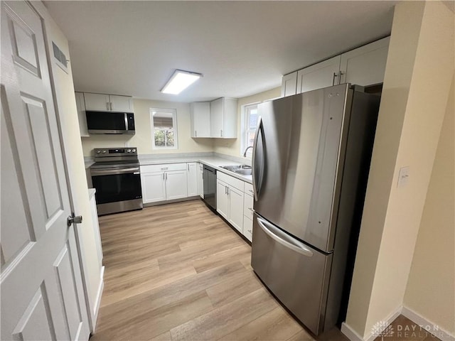 kitchen with white cabinets, stainless steel appliances, light hardwood / wood-style flooring, and sink