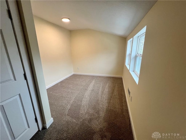 spare room with carpet floors and vaulted ceiling