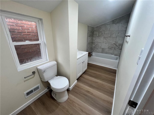 bathroom with hardwood / wood-style floors, vanity, vaulted ceiling, and toilet