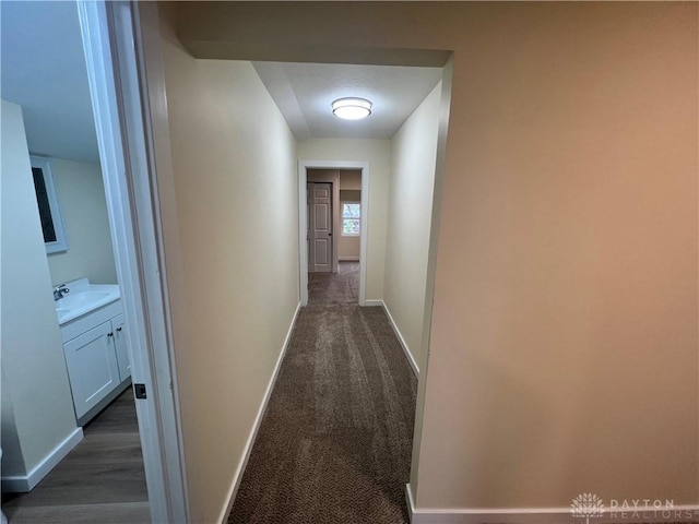 corridor with dark carpet and sink