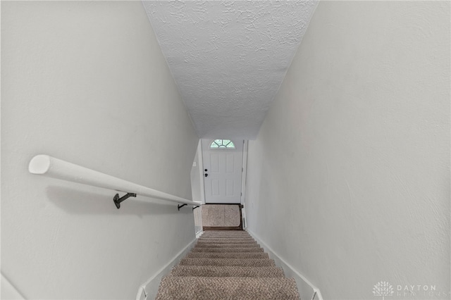 stairs featuring carpet flooring and a textured ceiling