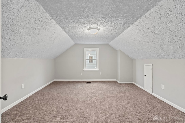 additional living space with carpet flooring, vaulted ceiling, and a textured ceiling