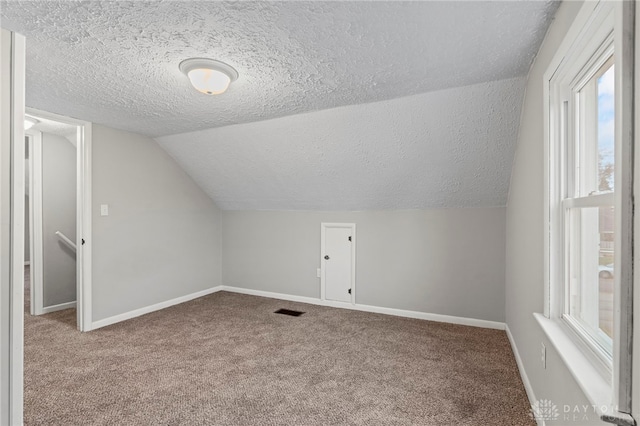 bonus room with a textured ceiling, carpet floors, and lofted ceiling