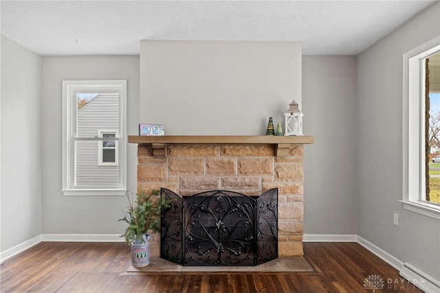 interior details with hardwood / wood-style flooring, a fireplace, a textured ceiling, and a baseboard heating unit