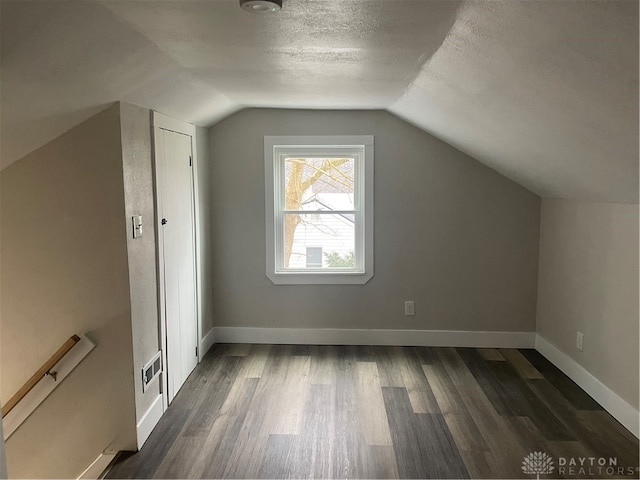 bonus room featuring dark hardwood / wood-style floors, a textured ceiling, and vaulted ceiling