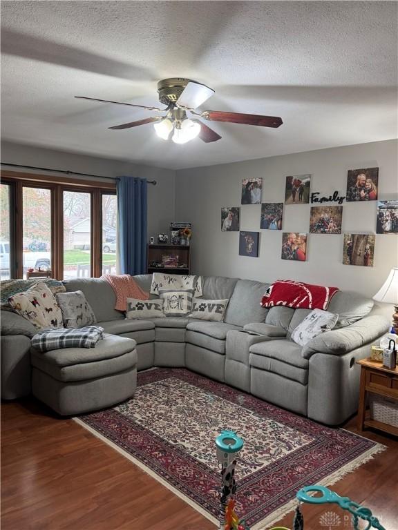 living room featuring ceiling fan, wood-type flooring, and a textured ceiling