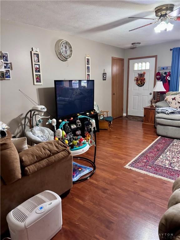 living room with ceiling fan, hardwood / wood-style flooring, and a textured ceiling