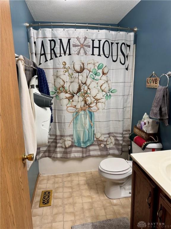 full bathroom featuring vanity, toilet, a textured ceiling, and shower / bath combo