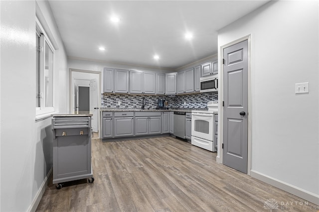 kitchen featuring tasteful backsplash, white appliances, sink, hardwood / wood-style flooring, and gray cabinets