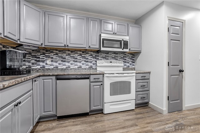 kitchen featuring decorative backsplash, appliances with stainless steel finishes, gray cabinets, and hardwood / wood-style flooring