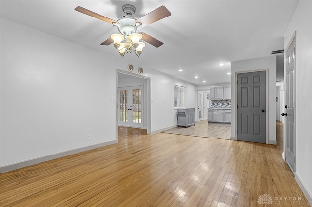 unfurnished living room with french doors, light hardwood / wood-style floors, and ceiling fan