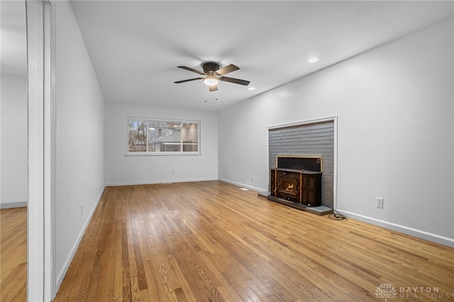 unfurnished living room featuring ceiling fan, a fireplace, and light wood-type flooring