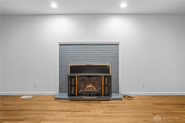 interior details featuring a brick fireplace and hardwood / wood-style flooring