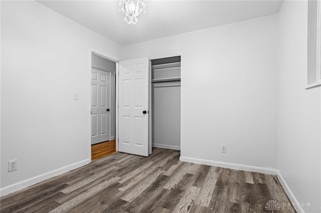 unfurnished bedroom with a closet, a notable chandelier, and hardwood / wood-style flooring