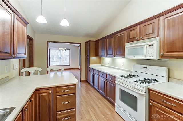 kitchen with decorative light fixtures, vaulted ceiling, white appliances, light hardwood / wood-style flooring, and a chandelier