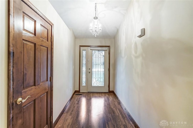 doorway to outside featuring an inviting chandelier and dark hardwood / wood-style flooring