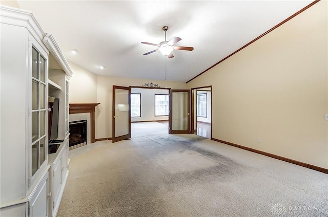 unfurnished living room featuring ceiling fan, light colored carpet, french doors, vaulted ceiling, and crown molding