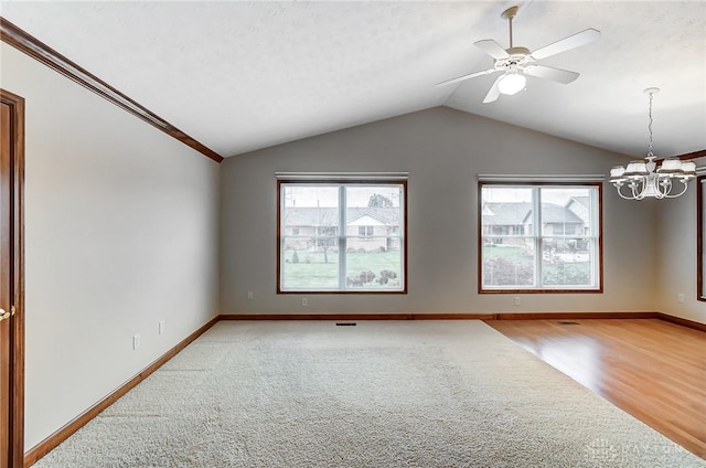 spare room featuring vaulted ceiling, light hardwood / wood-style floors, and ceiling fan with notable chandelier