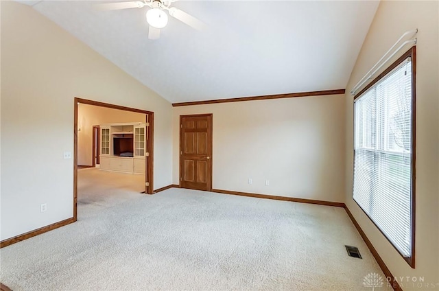 spare room with ceiling fan, light colored carpet, and vaulted ceiling