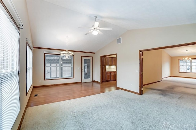 carpeted spare room featuring vaulted ceiling and ceiling fan with notable chandelier