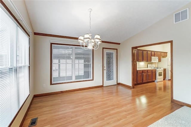 dining area with lofted ceiling, a wealth of natural light, an inviting chandelier, and light hardwood / wood-style flooring