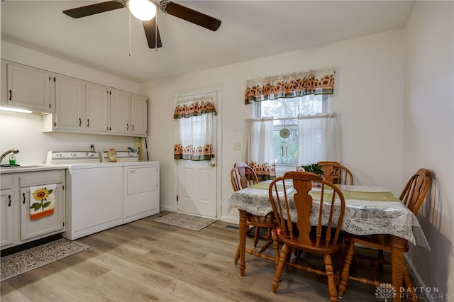 laundry room featuring ceiling fan, sink, cabinets, washing machine and dryer, and light hardwood / wood-style flooring