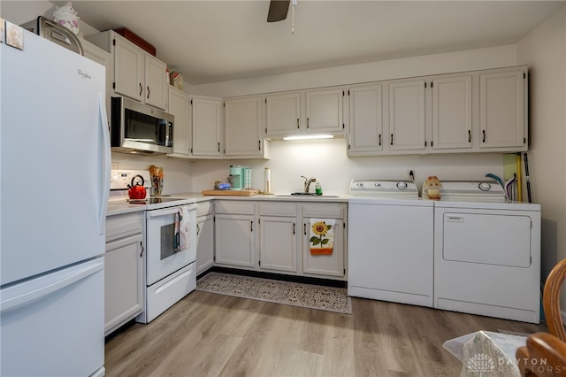 kitchen with white cabinetry, sink, washing machine and dryer, light hardwood / wood-style flooring, and white appliances