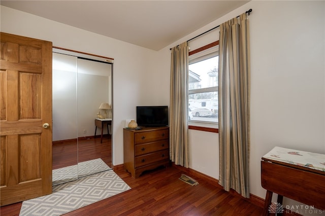 bedroom with dark hardwood / wood-style floors and a closet