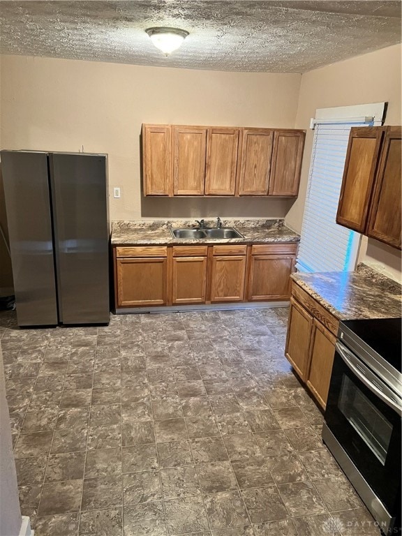 kitchen with a textured ceiling, stainless steel appliances, and sink