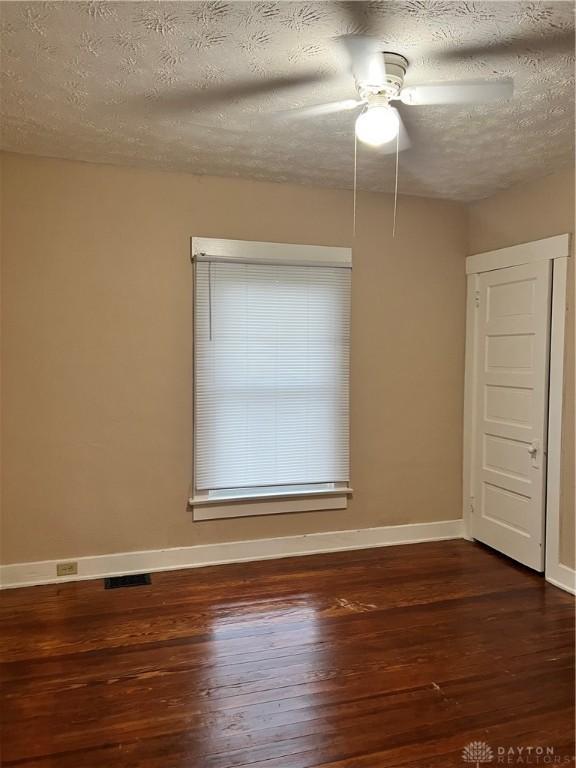 unfurnished room featuring ceiling fan, dark hardwood / wood-style flooring, and a textured ceiling