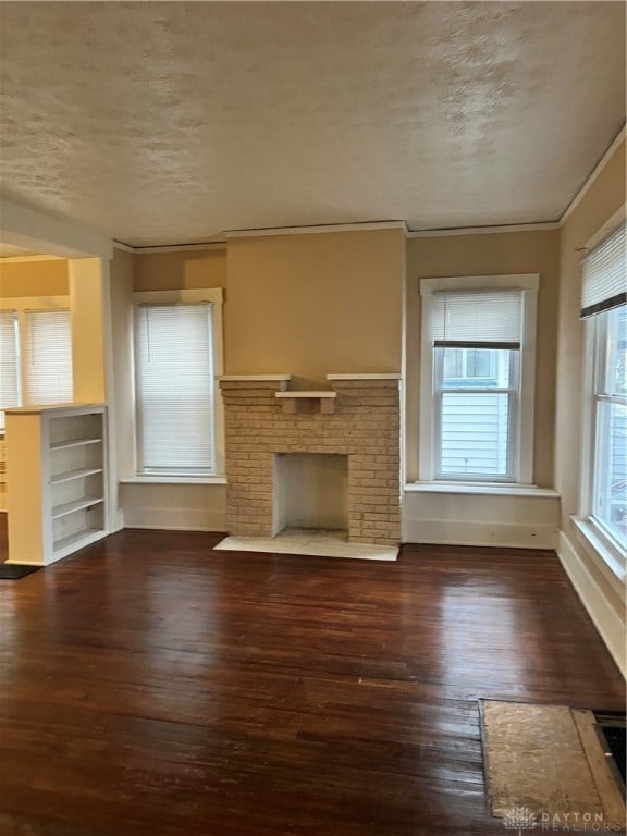 unfurnished living room with a fireplace, a textured ceiling, crown molding, and dark wood-type flooring