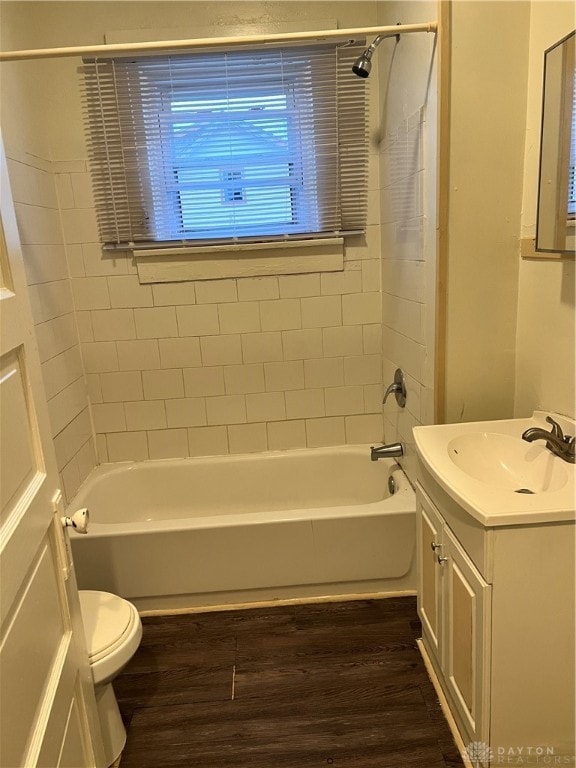 full bathroom with vanity, tiled shower / bath, hardwood / wood-style flooring, toilet, and a wealth of natural light