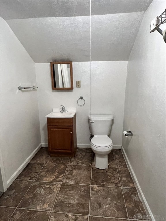 bathroom with toilet, a textured ceiling, vanity, and vaulted ceiling