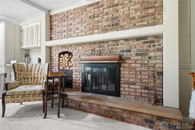 living area with carpet flooring, ornamental molding, brick wall, and a brick fireplace