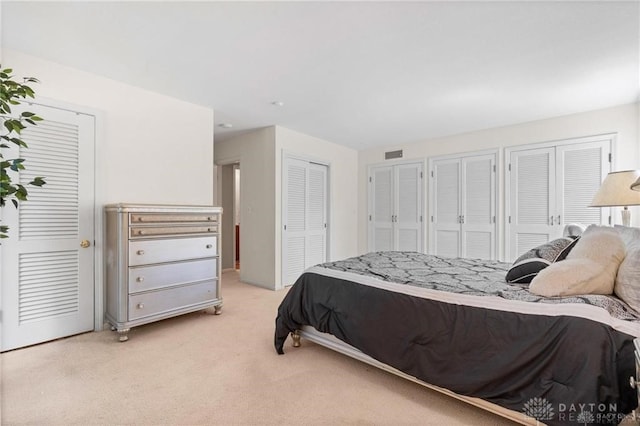 bedroom with light carpet and two closets