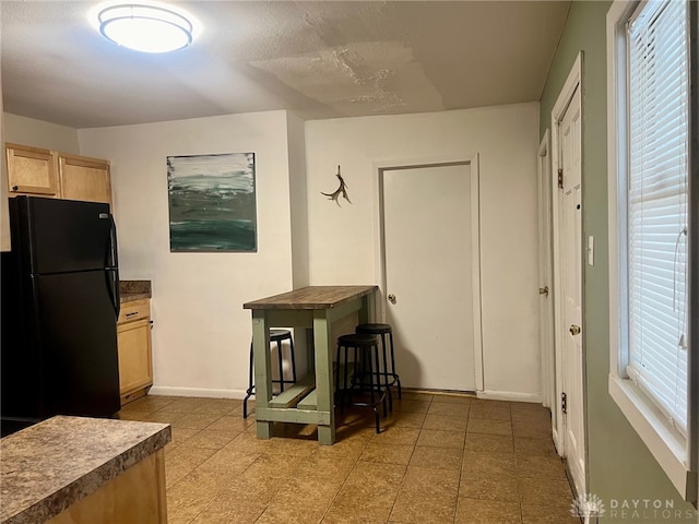 kitchen featuring black refrigerator and light brown cabinets