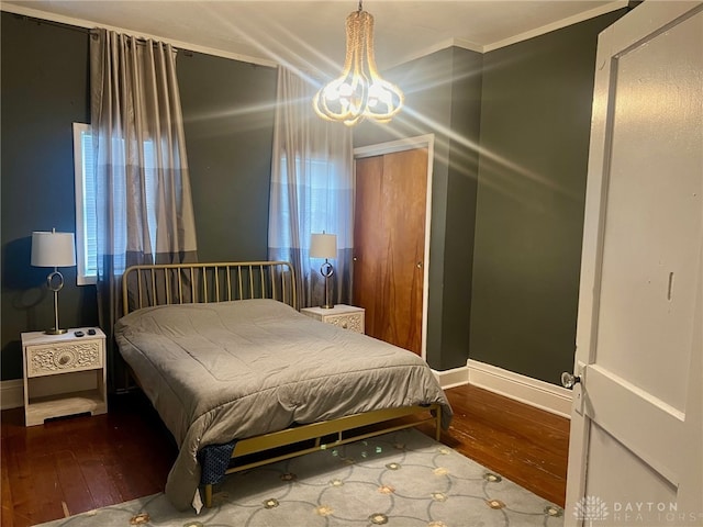 bedroom with hardwood / wood-style flooring, crown molding, and a chandelier