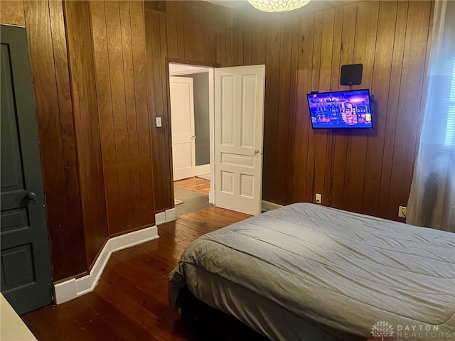 bedroom featuring dark hardwood / wood-style floors and wooden walls