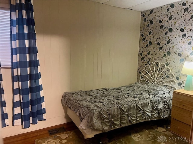 bedroom with a paneled ceiling and dark hardwood / wood-style floors