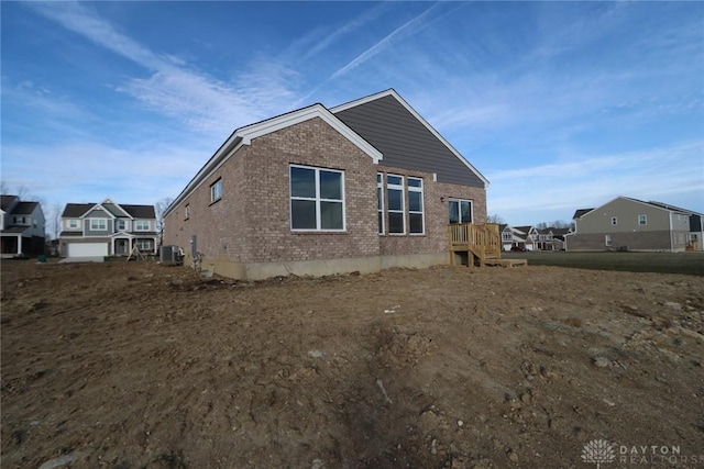 view of side of property featuring central air condition unit, a residential view, and brick siding