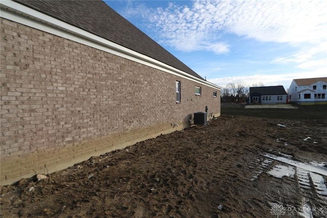 view of side of property featuring central AC and brick siding