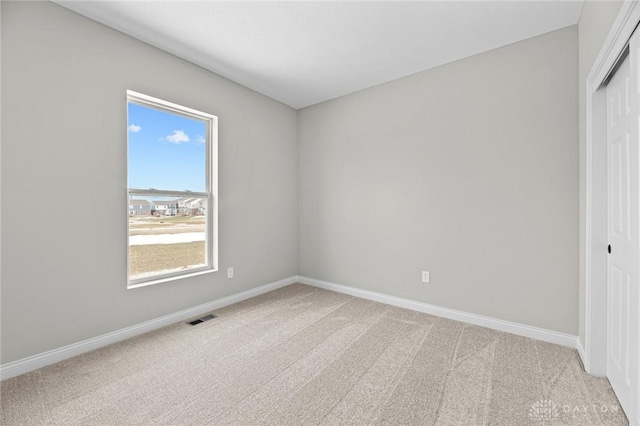 unfurnished bedroom with a closet, light carpet, visible vents, and baseboards