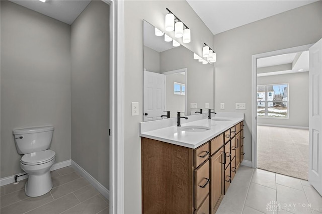 bathroom featuring tile patterned flooring, a sink, toilet, and double vanity