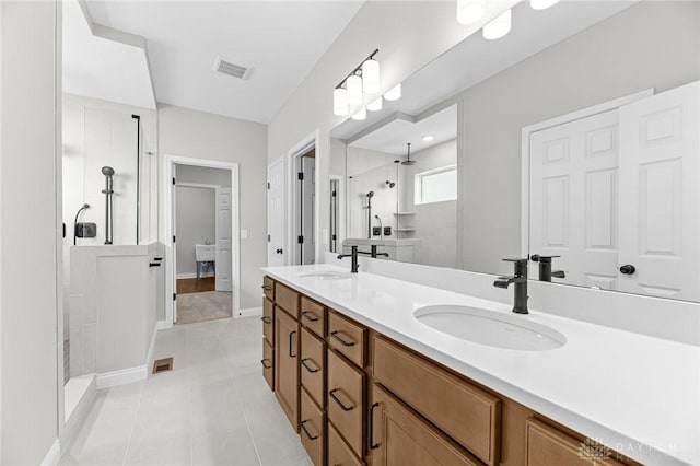 bathroom with double vanity, visible vents, a sink, a tile shower, and tile patterned floors