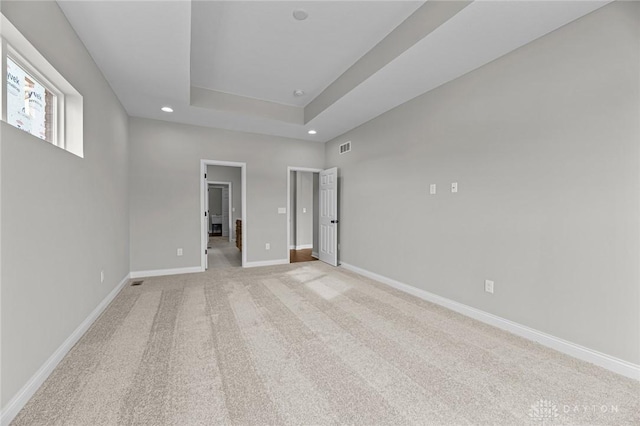 unfurnished bedroom featuring recessed lighting, a raised ceiling, light colored carpet, and baseboards