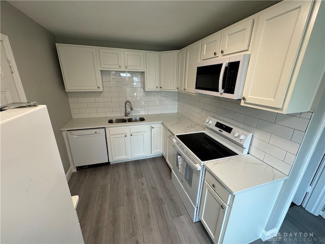 kitchen with white appliances, backsplash, white cabinets, sink, and light hardwood / wood-style floors