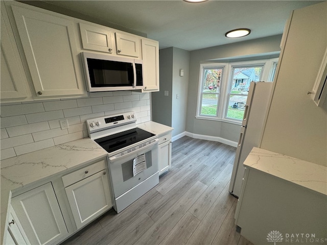 kitchen with light stone countertops, light hardwood / wood-style flooring, backsplash, white appliances, and white cabinets